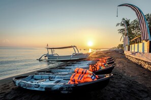A beach with boats lined up and a building with a checkered awning.