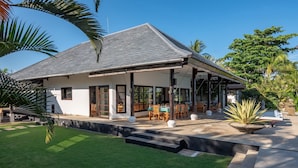 A modern house with a covered patio, a lawn, and a large plant in the foreground. - Beachfront pool villa: Free welcome dinner! With own boat! (Dencarik)