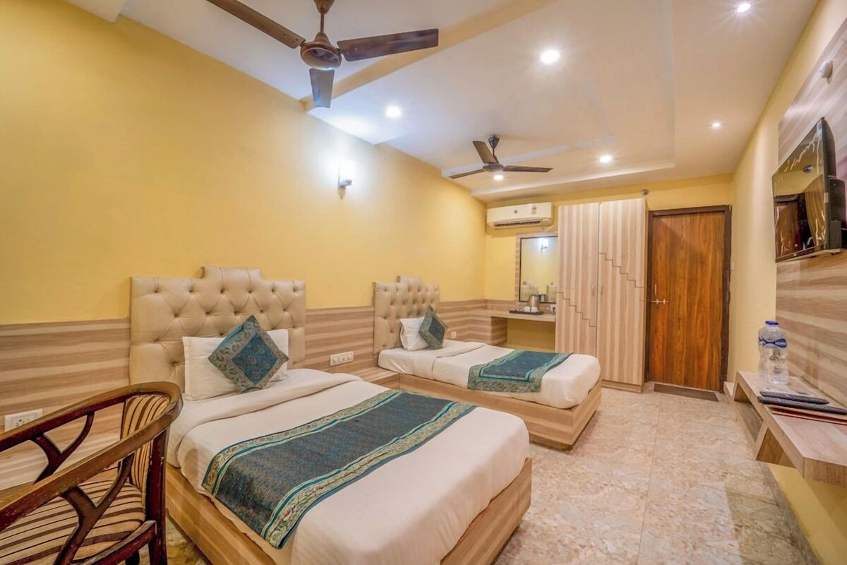 A hotel room with two beds, a ceiling fan, an air conditioning unit, and a wooden door.