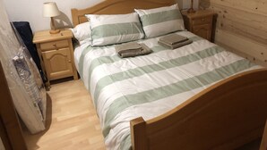 Una cama bien hecha con ropa de cama a rayas, dos mesitas de noche con lámparas y un cabecero de madera.