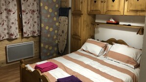 Una habitación tipo cabaña de madera con una cama, cortinas, un calentador y armarios de madera.