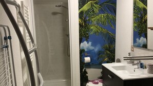Un baño con ducha, inodoro y lavadora.