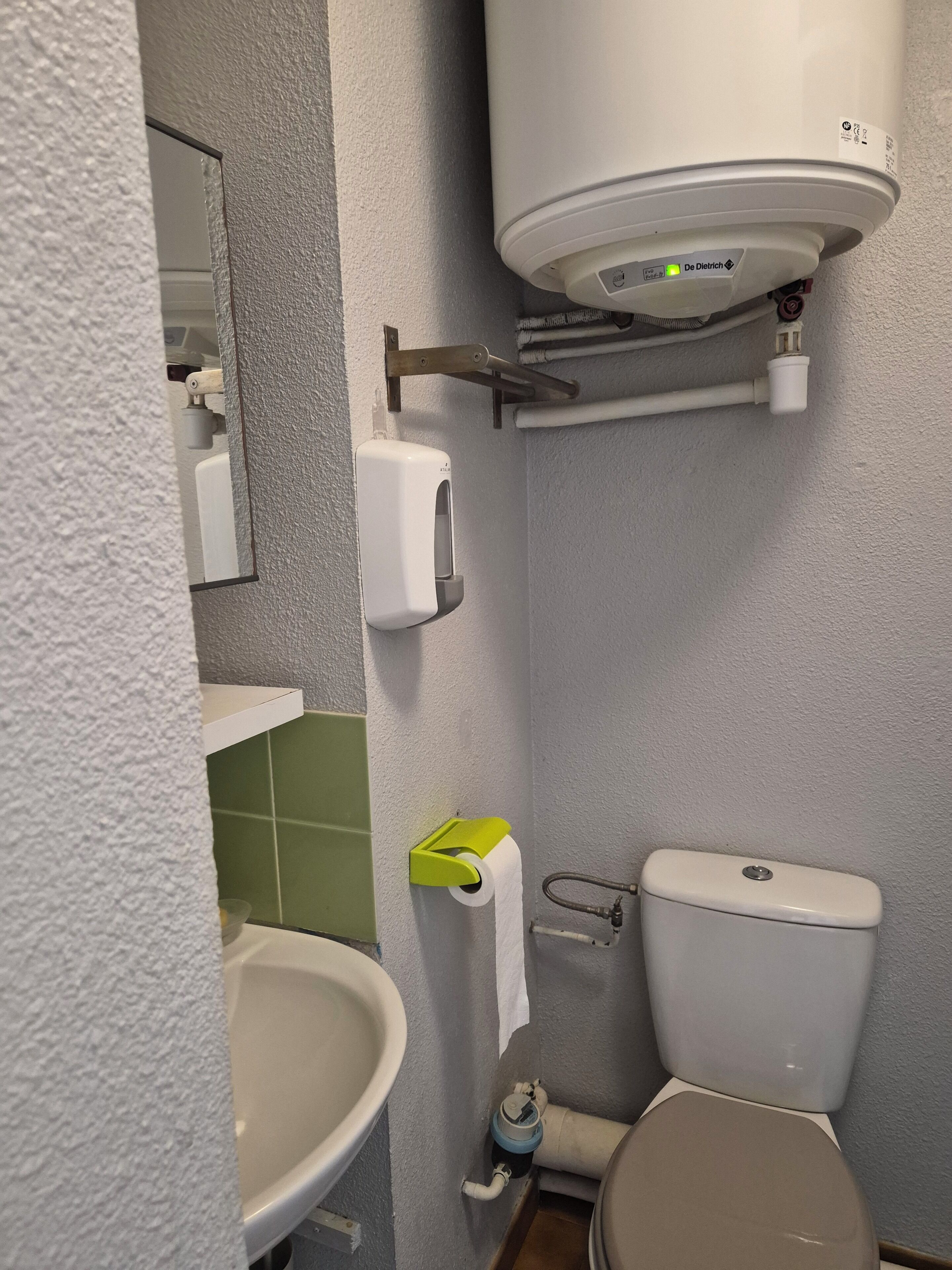 Un bagno con un water, un lavandino e un asciugamani ad aria montato a parete.