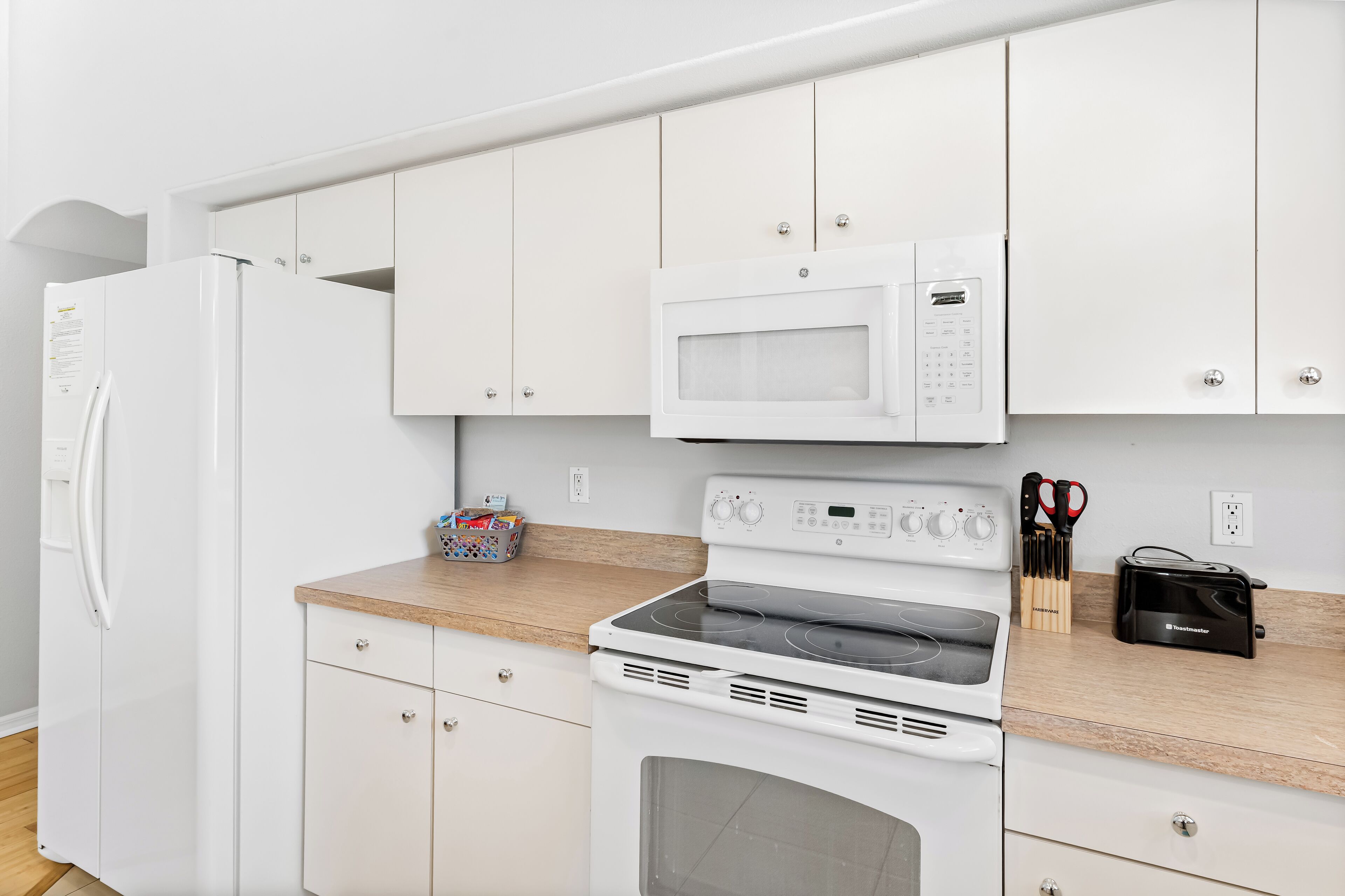 Una cucina moderna con elettrodomestici bianchi, tra cui frigorifero, forno a microonde e forno.