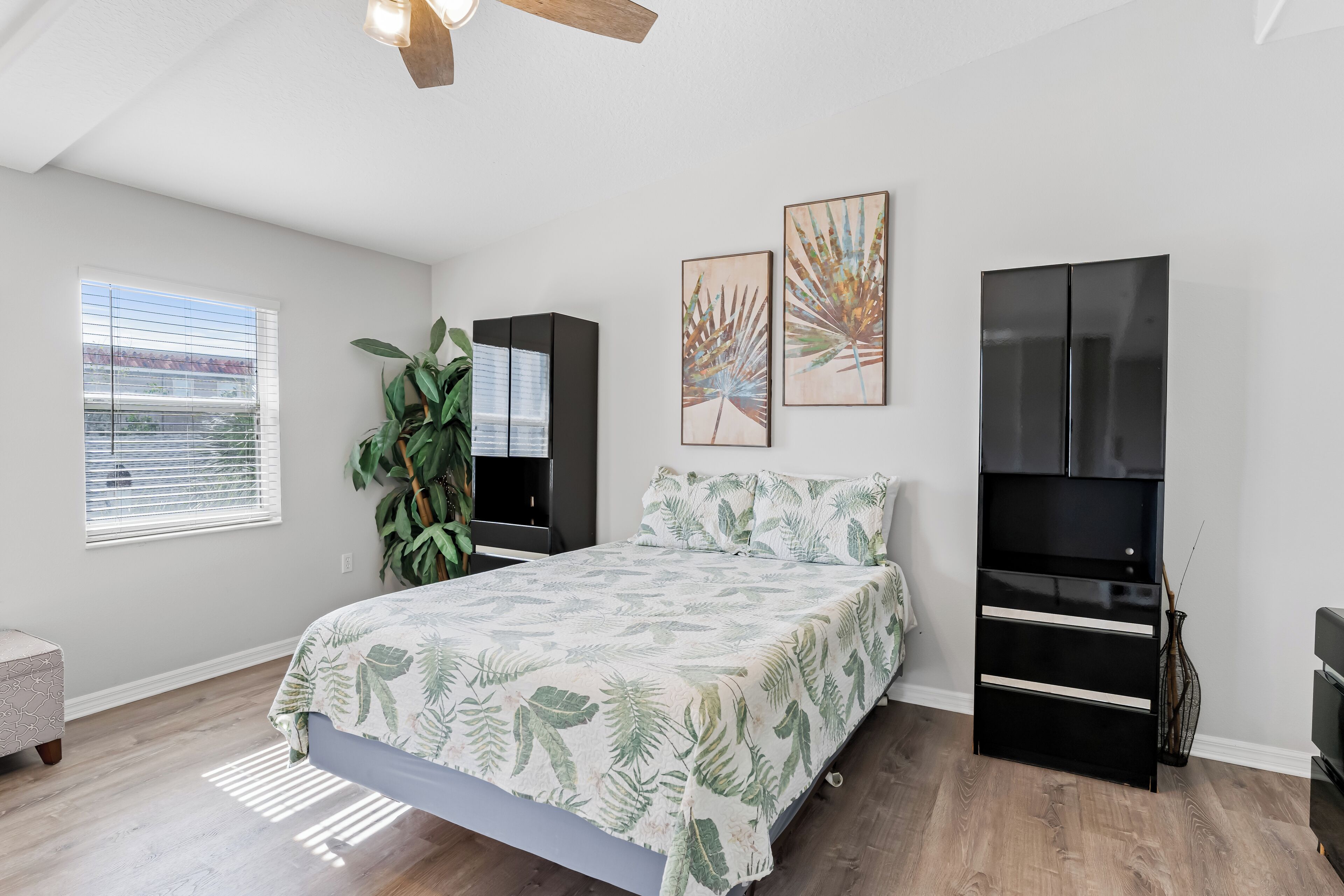 A bedroom with a bed, a large mirror, a wardrobe, and a window with blinds.