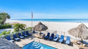 A beachside resort with a pool area, lounge chairs, and a view of the ocean.