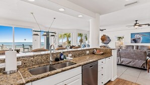A modern kitchen with granite countertops, stainless steel appliances, and a view of the ocean.