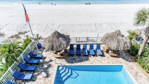 Un espace piscine avec des chaises longues, un drapeau et une vue sur la plage.