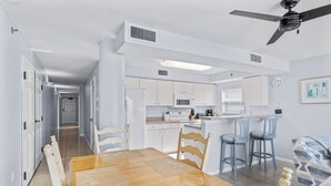 Une cuisine moderne avec des meubles blancs, un four à micro-ondes et un coin repas comprenant une table et des chaises en bois.