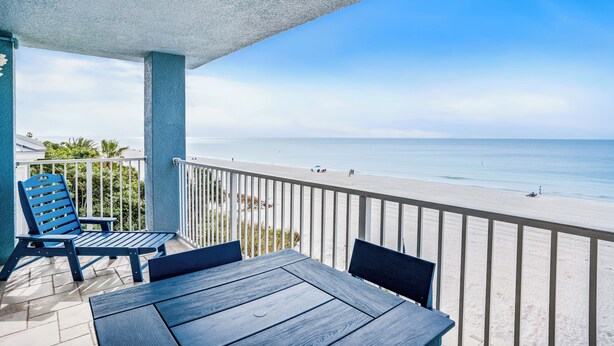 A balcony with a view of the beach, a table, and two chairs. - Sand Isle II Unit D-Corner Gulf Front 2bdr 2bath (Indian Rocks Beach)