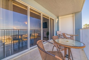 Relax on the ocean-view balcony with wicker chairs and a glass table, perfect for dining or unwinding.