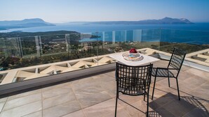 Una terraza con mesa y sillas que ofrece vistas panorámicas de un cuerpo de agua y montañas distantes.