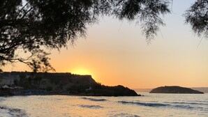 Una playa con un atardecer, olas y una isla distante.