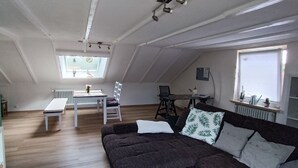 Un soggiorno moderno con un divano marrone scuro, un tavolo bianco e una parete verde decorativa.