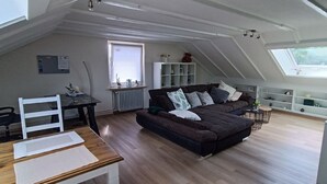Camera mansarda con un ampio letto, una scrivania e una sedia. Una finestra permette l'ingresso di luce naturale e offre vista all'esterno.
