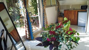 A room with a large window, a dining table, a kitchen area, and a potted plant. - Villa Oasis Abidjan (Abidjan)