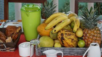 A table with a variety of fruits, a green tumbler, and a white pitcher.