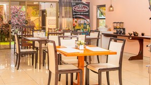 A restaurant with wooden tables and chairs, a large poster on the wall, and a coffee machine on the counter. - The Berkshire (Harare)