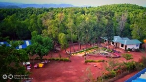 An aerial view of a hotel with a landscaped garden, a pool, and a view of the surrounding forest. - Viraz Valley (Kumta)