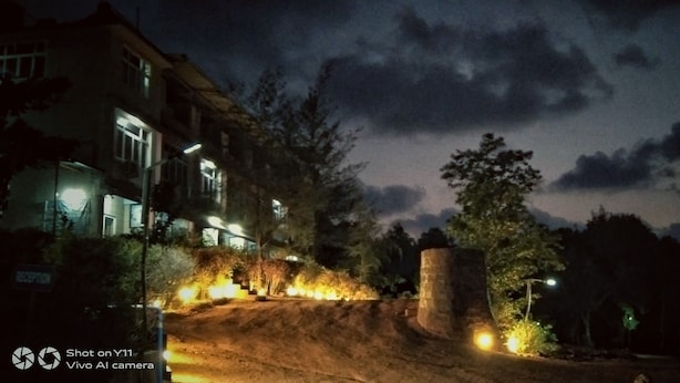 A nighttime scene with a reception area, a dirt path leading to a building, and a stone structure. - Viraz Valley (Kumta)