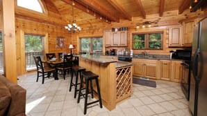 A wooden cabin interior with a kitchen, dining area, and bar.