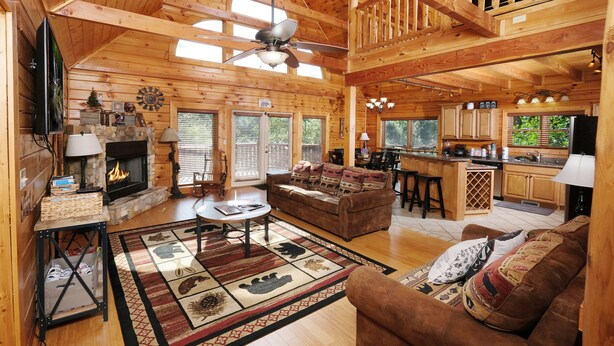 A spacious log cabin interior with a living room, kitchen, and dining area.