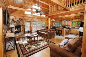 A spacious log cabin interior with a living room, kitchen, and dining area.