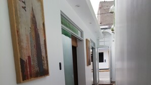 A hallway with a tiled floor, a painting of a cityscape, and a door leading to another room. - Casa Blue Hill Beach (Cerro Azul)