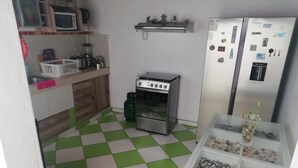 A kitchen with a checkered floor, a gas stove, a refrigerator, and a small table with a decorative item. - Casa Blue Hill Beach (Cerro Azul)
