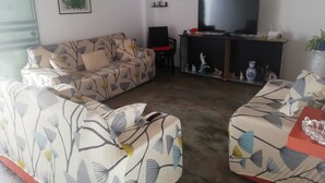 A living room with a sofa, a television, and a small table. - Casa Blue Hill Beach (Cerro Azul)
