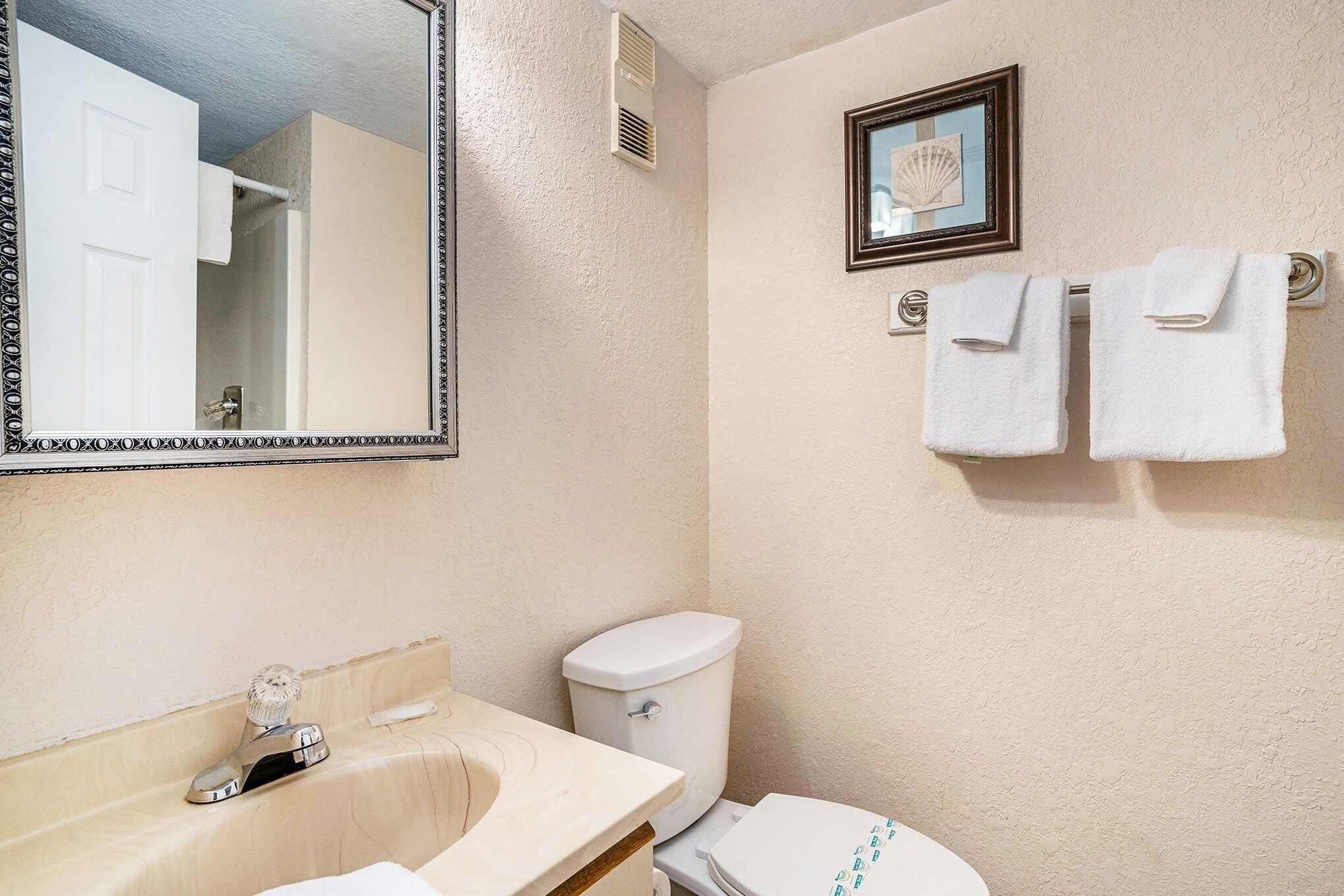 A bathroom with a sink, toilet, and a mirror.