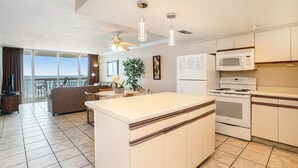 Une cuisine moderne dotée d’un îlot central, de meubles blancs, d’un four à micro-ondes, d’une cuisinière et d’un ventilateur de plafond.