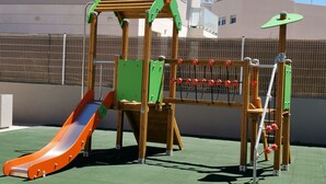 A playground with a slide, climbing structures, and a netted area. - Holiday apartment Lime Javea - Golden star (Xàbia)