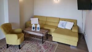 A living room with a yellow sofa, a yellow armchair, a wooden coffee table, and two wall-mounted lights. - Holiday apartment Lime Javea - Golden star (Xàbia)
