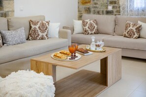 Una sala de estar con una mesa de centro de madera, dos sofás con cojines estampados y una alfombra blanca mullida.