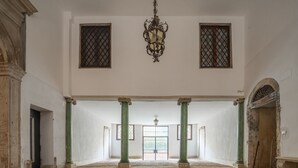 A spacious hall with a tiled floor, green columns, and a chandelier. - Apartment Donna Mathilde (Venezia)