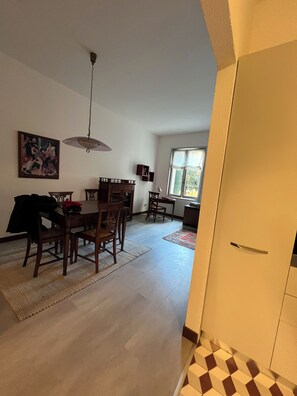 A dining area with a wooden table and chairs, a hanging light fixture, and a painting on the wall. - Apartment Donna Mathilde (Venezia)