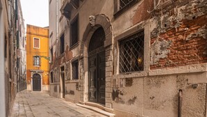 A narrow street with historic buildings, including a yellow building and a building with a black door and arched windows. - Apartment Donna Mathilde (Venezia)