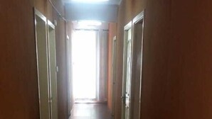 A long, narrow hallway with doors on both sides, leading to a bright exit at the end. - Hôtel le corail (Port Louis)