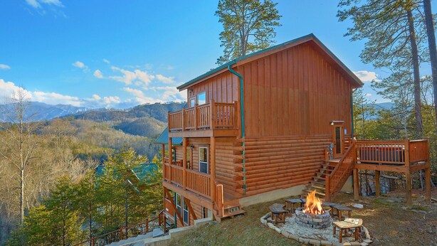 A log cabin with a balcony, a fire pit, and a view of the mountains. - Reindeer Bay: Private Pool, Amazing Views, Games (PIgeon Forge)