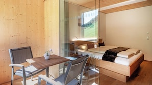 Une chambre moderne avec un mur en verre, un plafond en bois, un lit, une table de chevet et une chaise.