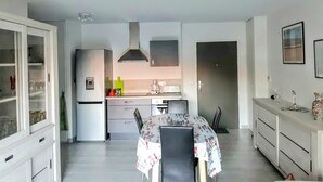 A modern kitchen with a dining area, featuring a refrigerator, stove, cabinets, and a table set for dining. - Flat for 4 , 150m from the beach in Sion (Saint-Hilaire-de-Riez)