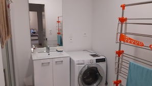 A compact laundry room with a washing machine, a sink, and a drying rack. - Flat for 4 , 150m from the beach in Sion (Saint-Hilaire-de-Riez)