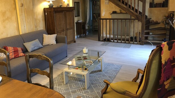 A cozy living room with a sofa, chairs, a coffee table, and a staircase leading to a lower level. - Large terraced house, with garden, in quiet area (Dijon)