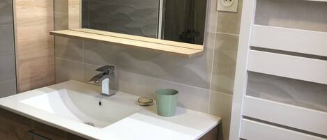 A bathroom with a white sink, a mirror, and a towel rack.