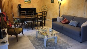 A living room with a sofa, coffee table, and chairs. There is a dining table with chairs, a chandelier, and a lamp. - Large terraced house, with garden, in quiet area (Dijon)