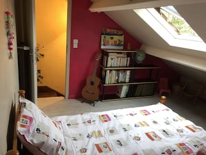 A bedroom with a sloped ceiling, a guitar, a bookshelf, and a bed with a patterned bedspread. - Large terraced house, with garden, in quiet area (Dijon)