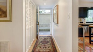 A hallway with a patterned rug, a door with louvered shutters, and a kitchen area with a dishwasher. - Spacious Garden Unit on Historic Jones Street! (Savannah)