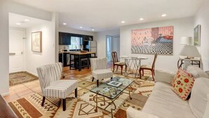 A living room with a sofa, armchairs, a coffee table, and a dining area with a table and chairs. - Spacious Garden Unit on Historic Jones Street! (Savannah)