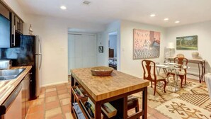 A modern kitchen with a dining area, including a table with chairs and a rug. - Spacious Garden Unit on Historic Jones Street! (Savannah)
